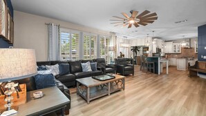 Ein geräumiges Wohnzimmer mit Sofa, Couchtisch und Essbereich, im Hintergrund eine Küche.