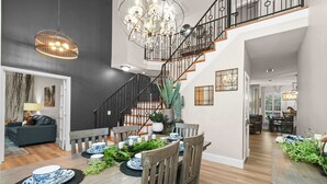 Ein Essbereich mit einem Holztisch, gedeckt für vier Personen, umgeben von Stühlen, einer Pendelleuchte und einer Treppe zu einer weiteren Ebene.