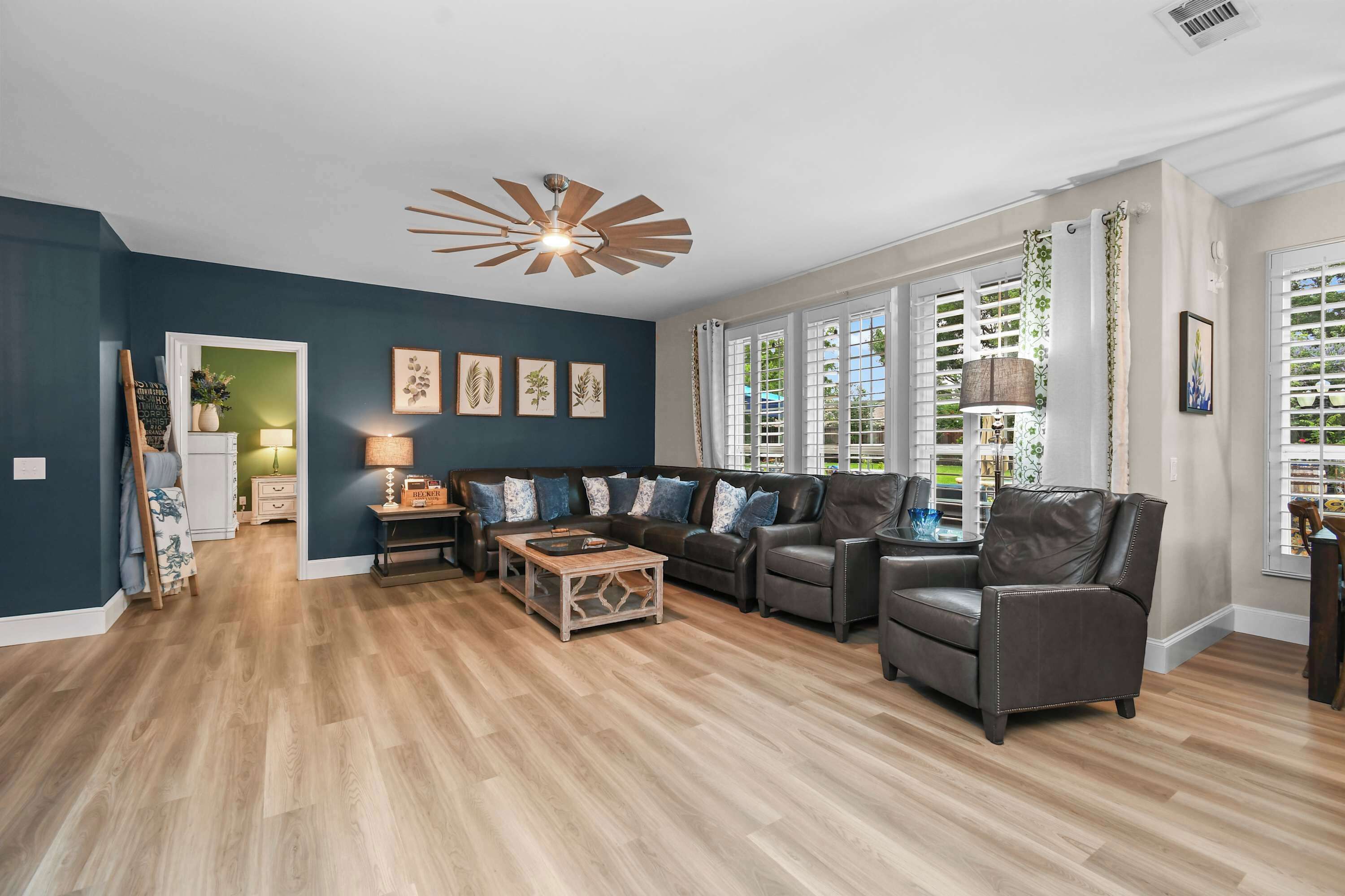 A living room with a sectional sofa, a coffee table, and a ceiling fan.