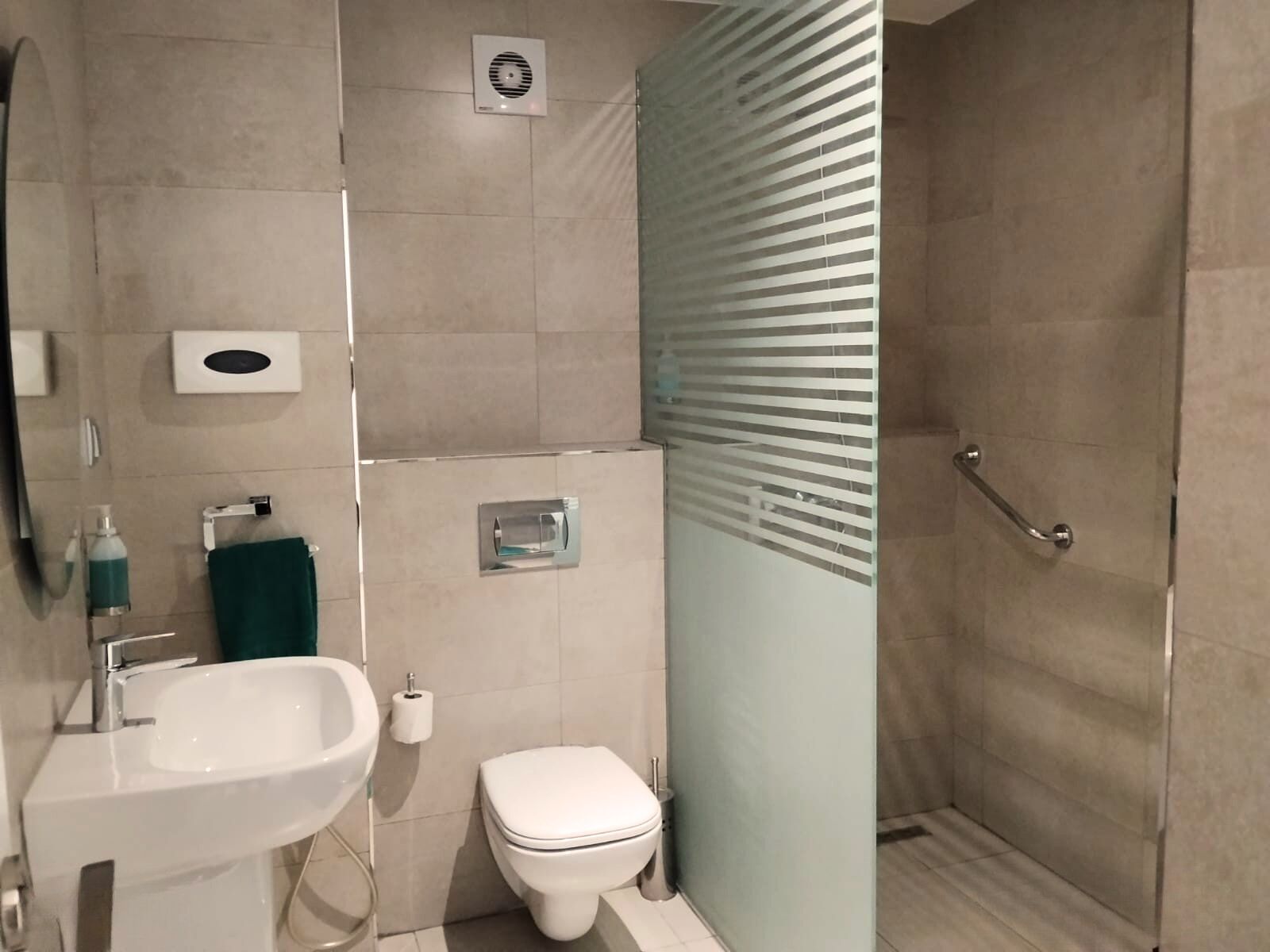 Un baño moderno con lavamanos, inodoro y ducha.
