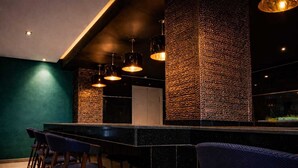 A bar area with a high counter, multiple hanging pendant lights, and bar stools.