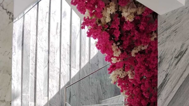 A marble staircase with glass railings and pink flowers.