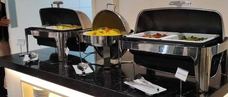 Un buffet composé de plusieurs récipients contenant différents aliments, d’une vitrine réfrigérée et d’un système de ventilation.