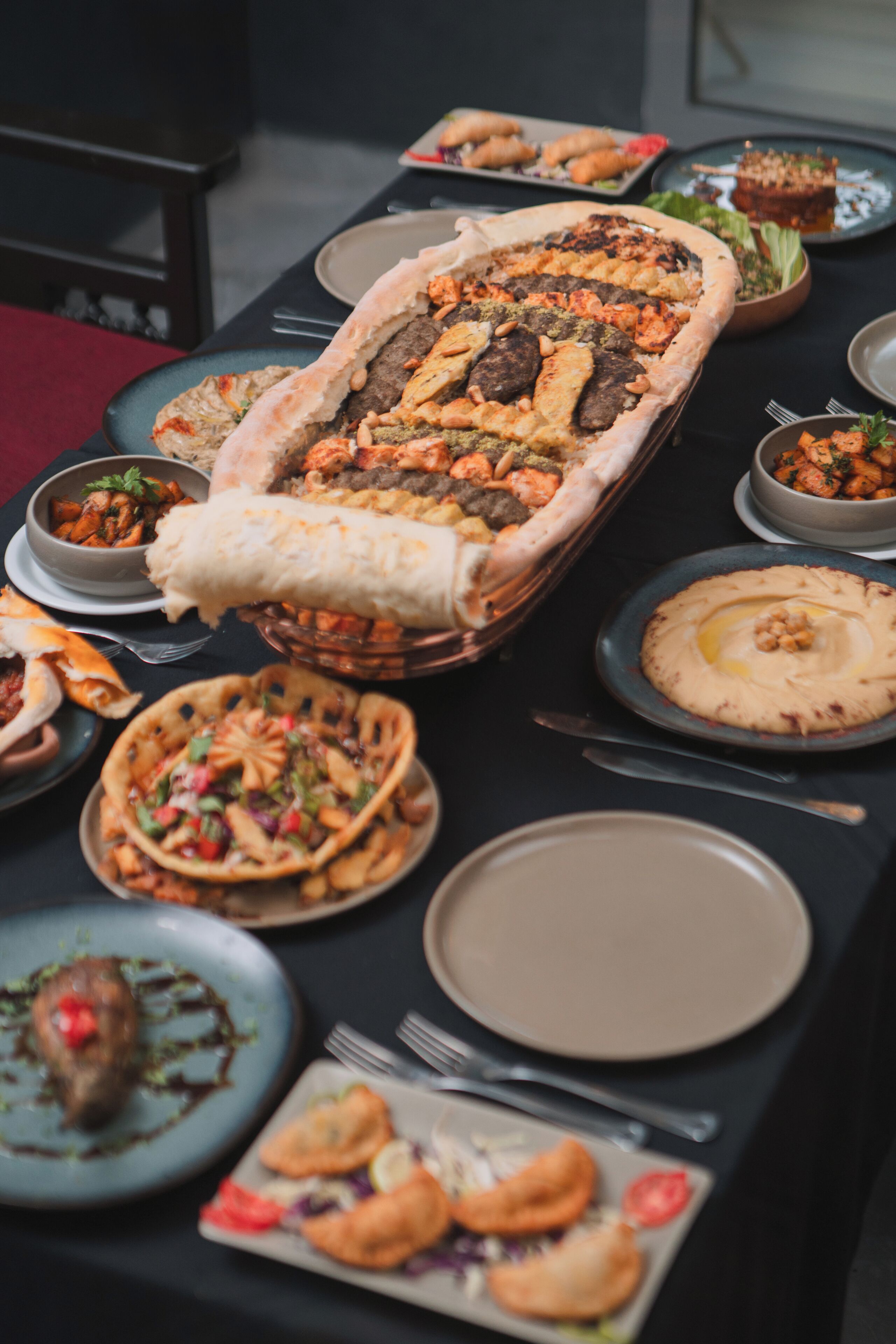 Een gedekte tafel met diverse gerechten, waaronder een groot schaal vol eten, kommen en borden.