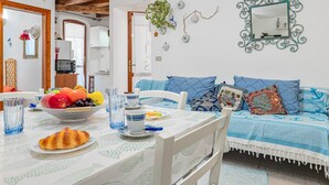 A dining area with a table set for breakfast, a sofa with patterned cushions, and a decorative mirror on the wall. - Apartment 'Del Tirreno' with Private Terrace and Air Conditioning (San Teodoro)