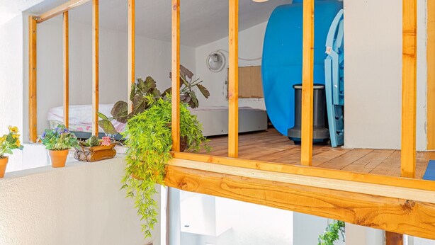 A wooden balcony with a view of a bedroom, including a bed and a washing machine. - Apartment 'Del Tirreno' with Private Terrace and Air Conditioning (San Teodoro)