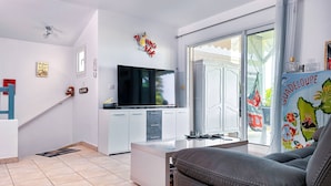 Una sala de estar moderna con un televisor de pantalla plana, un sofá y un comedor con un armario blanco.