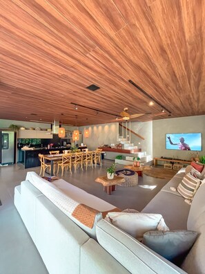 Ein stilvoller Wohnraum mit Holzboden, Essbereich, Küche und einer Sitzecke mit Fernseher.