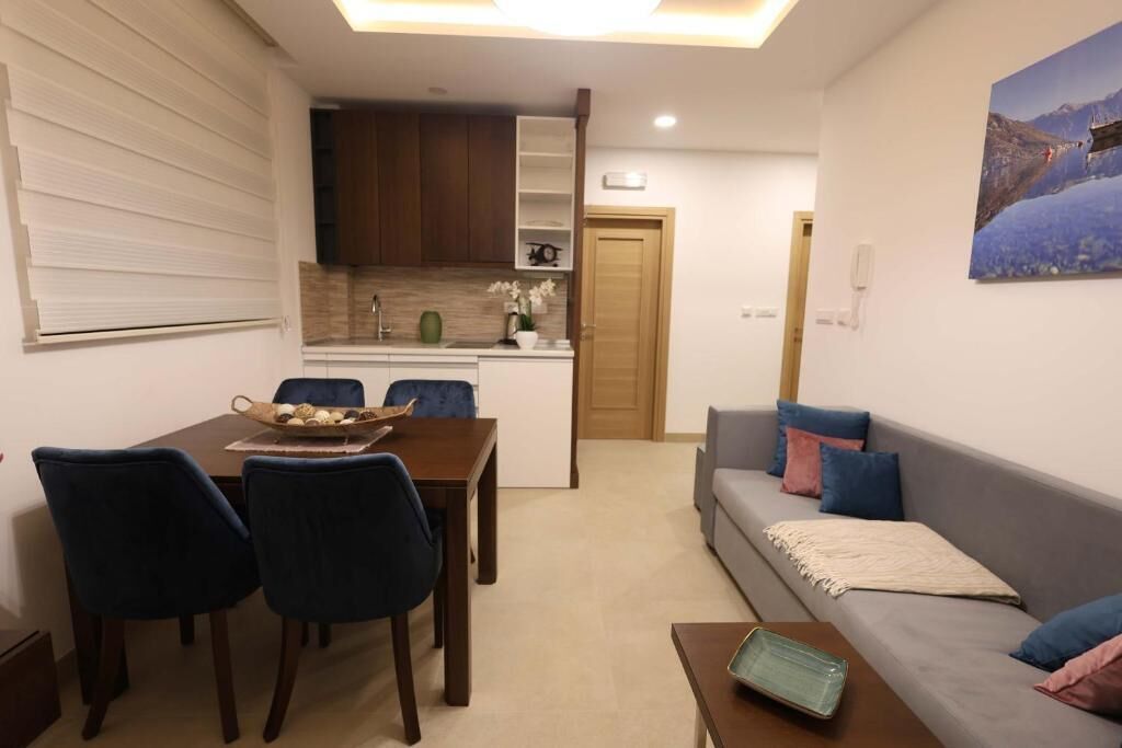 Un espacio habitable compacto con comedor, kitchenette, sofá y un cuadro en la pared.