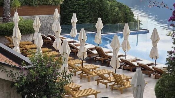 A pool area with lounge chairs and umbrellas, overlooking a lake with mountains in the background. - Bellezza Residence & Spa Kotor (Kotor)