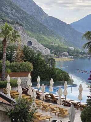 A pool area with lounge chairs and umbrellas, overlooking a lake with mountains in the background. - Bellezza Residence & Spa Kotor (Kotor)