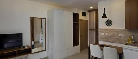 Una habitación de hotel moderna con cama, televisión, escritorio con sillas y kitchenette.