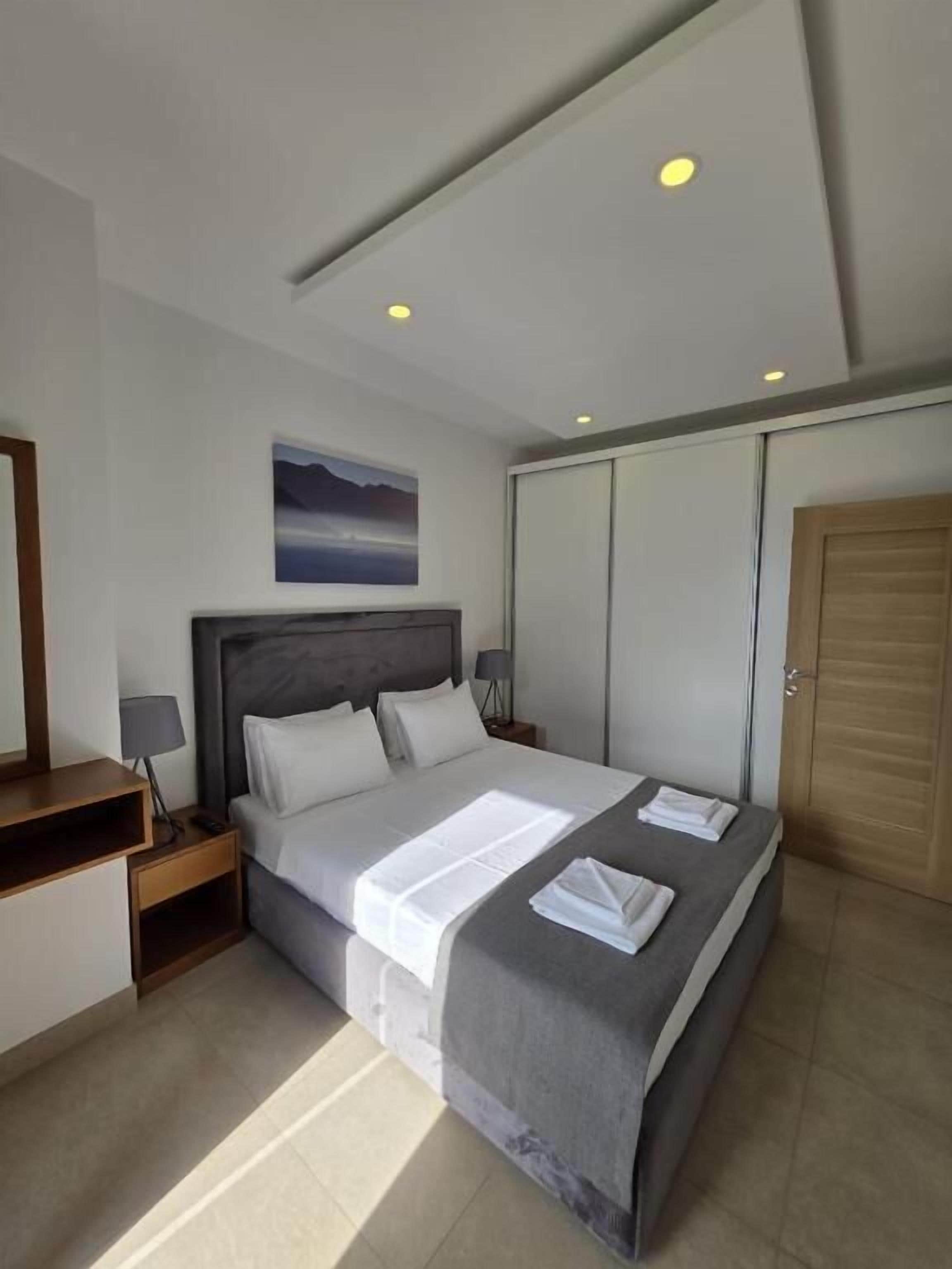 Una habitación de hotel moderna con una cama grande, una mesita de noche, un escritorio, un armario y un cuadro en la pared.