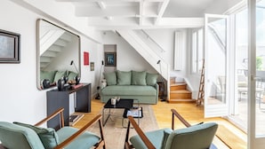 En moderne stue med trappe, grøn sofa og trægulv.