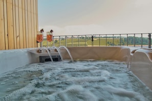 Ein Whirlpool mit einer Holzverkleidung und Blick auf eine grĂŒne Landschaft.