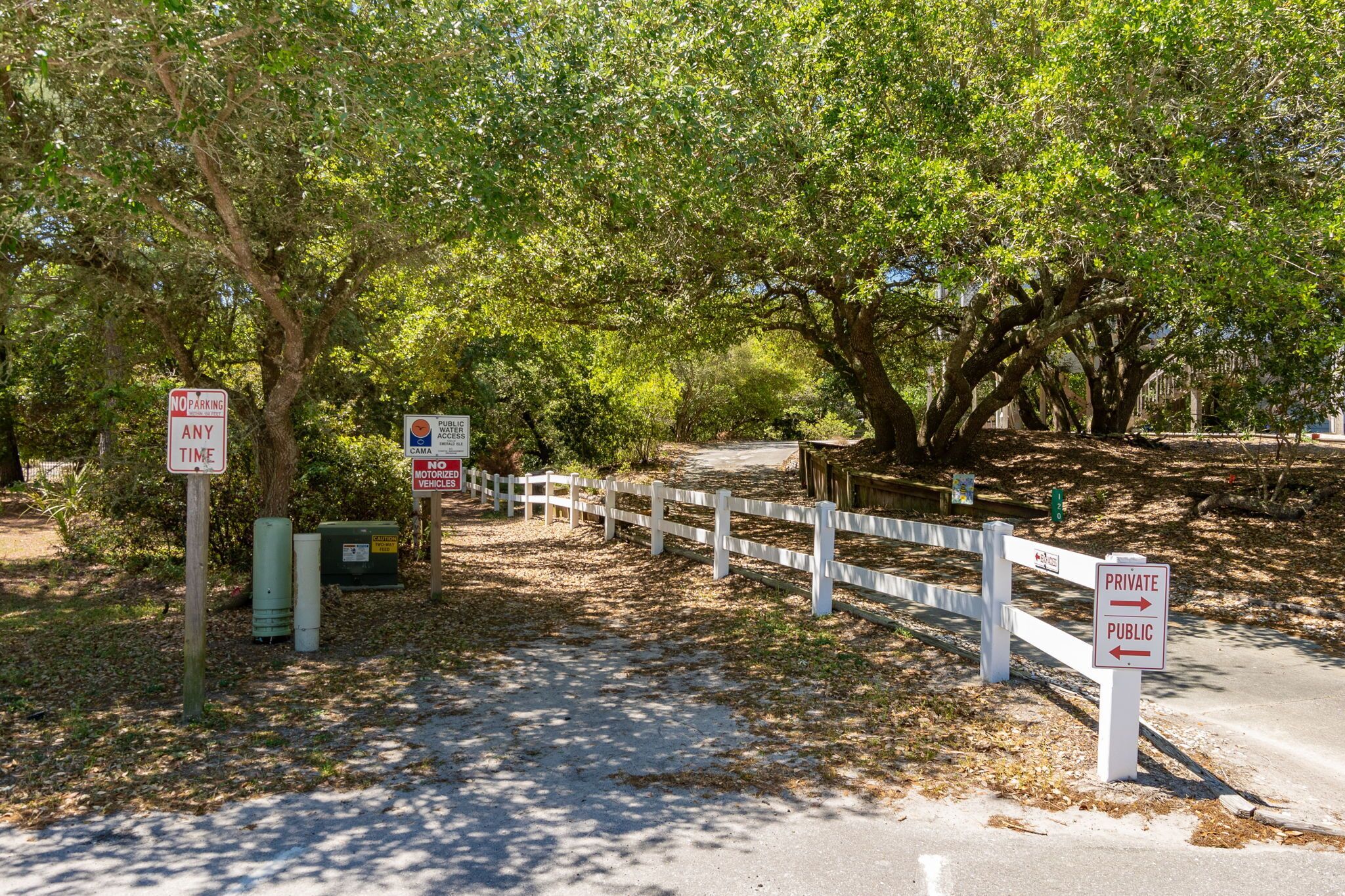 A gated area with signs indicating no parking and private/public access.