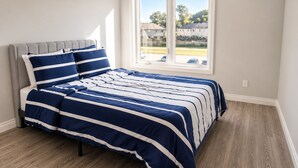 Un dormitorio con cama, ventana y vista a una zona residencial.