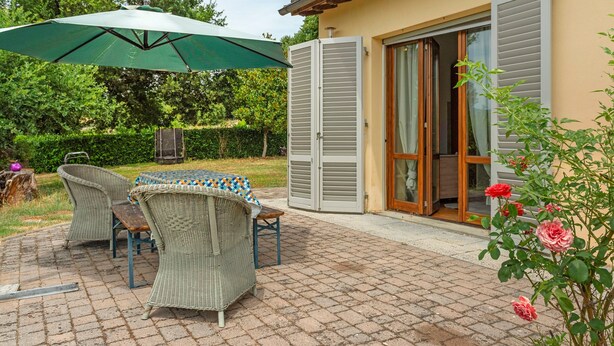 Une terrasse extérieure aménagée avec des meubles en osier, une table et un parasol vert.