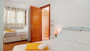 Une chambre d’hôtel comprenant un lit, une table de chevet avec une lampe, une armoire et une porte donnant sur une autre pièce.
