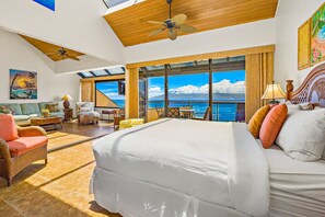 Ein geräumiges Schlafzimmer mit einem großen Bett, einem Balkon mit Meerblick und einem Essbereich mit Tisch und Stühlen.