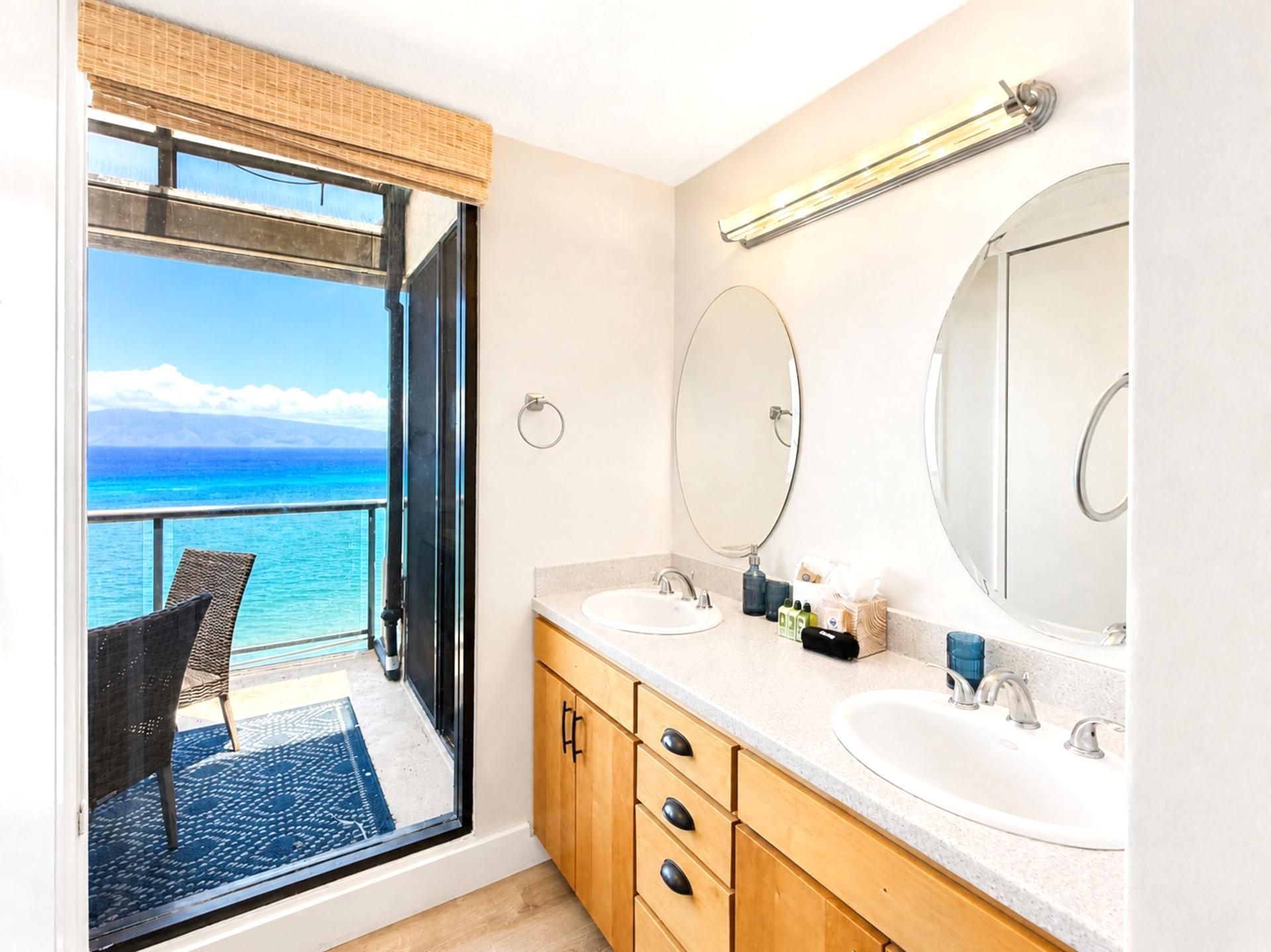Une salle de bain avec une grande fenêtre, deux lavabos et un miroir.