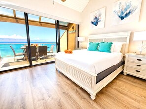 A bedroom with a large bed, a nightstand, a chair, a table, and a view of the ocean. - Sands of Kahana 2 Oceanfront Villas, Sleeps 16 | Car Incl. w/ 6 nights | ML-4052 by KBM (Lahaina)