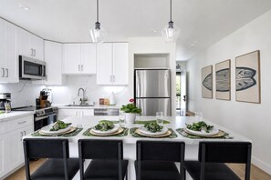 A modern kitchen with white cabinets, stainless steel appliances, and a central island with seating. - Kuilima Estates 2 Golf View Villas, Sleeps 16 | Car Incl. w/ 6 Nights | KUL ML-4046 by KBM (Kahuku)