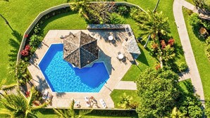 An aerial view of a swimming pool with a hexagonal deck, surrounded by palm trees and a garden. - Kuilima Estates 2 Golf View Villas, Sleeps 16 | Car Incl. w/ 6 Nights | KUL ML-4046 by KBM (Kahuku)