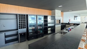 A modern kitchen with a central island, built-in refrigerators, and a wooden accent wall. - Hotel Bonfim (Silvânia)