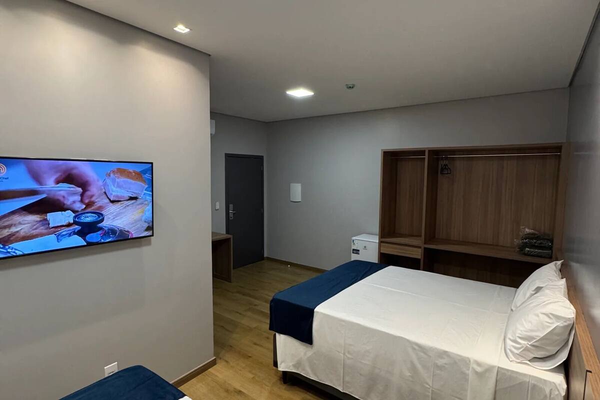 Habitación de hotel con dos camas, televisor, suelo de madera y armarios empotrados.
