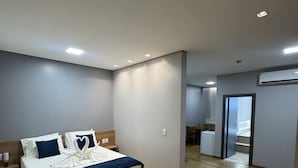 A modern hotel room with a large bed, bedside tables, a wardrobe, and a bathroom visible through an open door. - Hotel Bonfim (Silvânia)