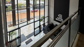 A hotel interior with large windows, a staircase, and a view of the outside. - Hotel Bonfim (Silvânia)