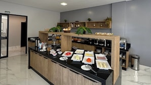 A modern hotel room with a marble floor, a central island with breakfast items, a wooden cabinet, and a 'SALIDA' sign. - Hotel Bonfim (Silvânia)