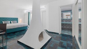 Une chambre moderne dotée d’un grand lit, d’une colonne blanche au design original et de carreaux de sol à motifs.