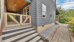 Een huis met een houten terras, stenen trappen en een stenen muur.