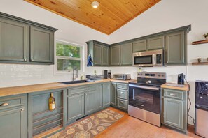 A kitchen with green cabinets, a microwave, an oven, and a wooden ceiling. - Woodland Cabin Retreat, Near Douglas Lake, Fire Pit (Dandridge)