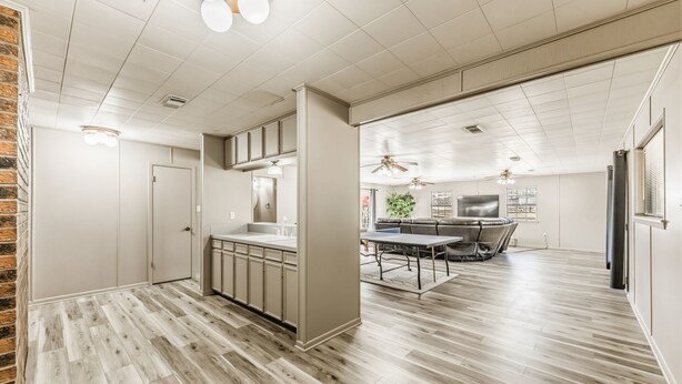 A modern kitchen with a central island, a dining area with a table and chairs, and a living space with a sofa and TV. - Hoofs and Horns Private Ranch (Huntsville)