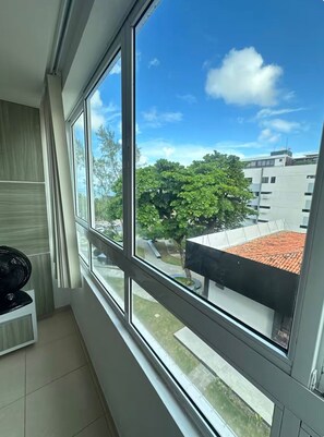 Ein Zimmer mit einem großen Fenster, einem Heizkörper und einem schwarzen Ventilator.