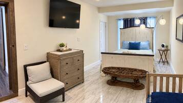 A bedroom with a bed, dresser, television, and a small table.