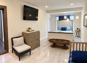 A bedroom with a bed, dresser, television, and a small table.