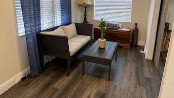 A living room with a dark wood floor, a sofa, a coffee table, and a ceiling fan.