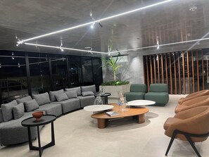 A modern interior with a grey sofa, a coffee table, and green armchairs. - HIT 202 - Sophisticated apartment with ocean views on Cabo Branco beach. (João Pessoa)
