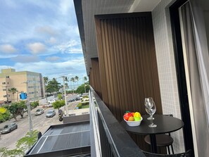 A balcony with a table, a bowl of fruit, and a wine glass. - HIT 202 - Sophisticated apartment with ocean views on Cabo Branco beach. (João Pessoa)