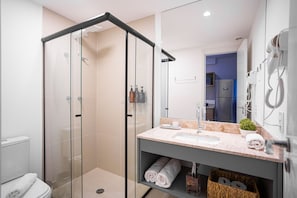 Un baño moderno con ducha de mampara de vidrio, lavabo con encimera de mármol y espejo.