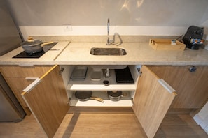 Una cocina compacta con lavamanos, estufa y armarios de almacenamiento.