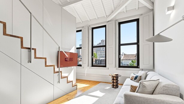 Un interno moderno con una scala, un divano e un cartello con la scritta 'GUEST READY'.