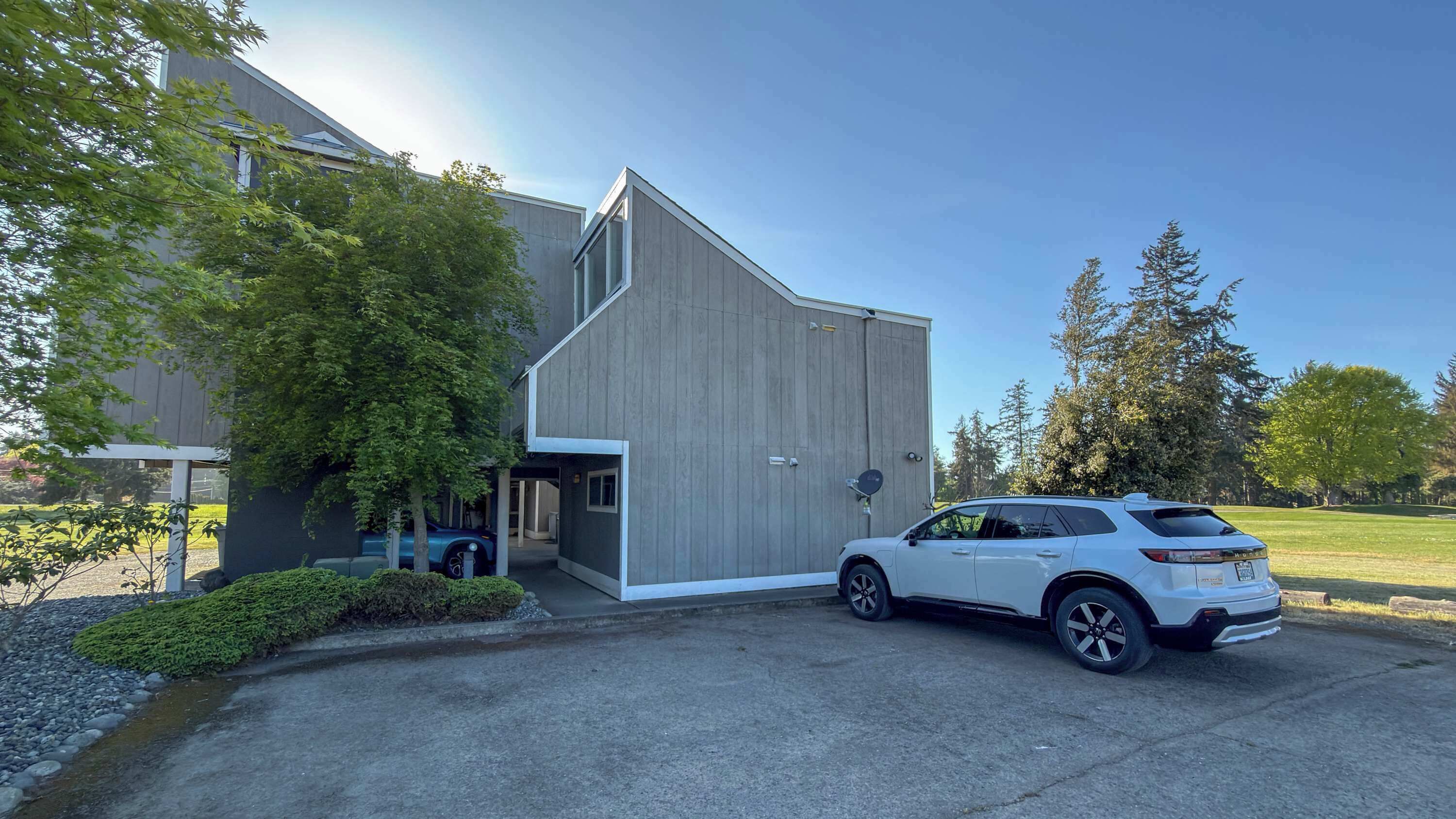 Un bâtiment moderne doté d’un grand portail de garage, d’un VUS garé devant et d’une pelouse bien entretenue.