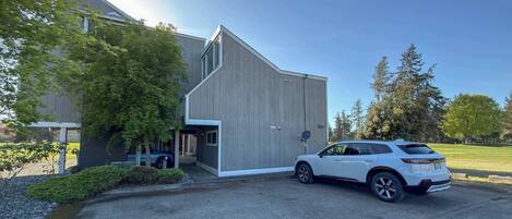 Un bâtiment moderne doté d’un grand portail de garage, d’un VUS garé devant et d’une pelouse bien entretenue.