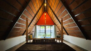 An attic bedroom with a sloped ceiling, a large window, and a wooden railing. - Oh-Bali Villa by Travent Mug (Ramanagara)