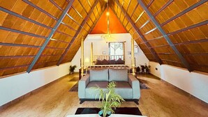 An attic room with a sloped ceiling, a sofa, a plant, and a window. - Oh-Bali Villa by Travent Mug (Ramanagara)